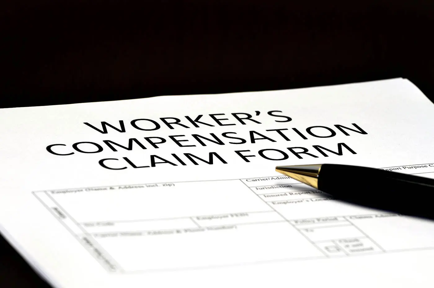 Workers' compensation claim form with a pen